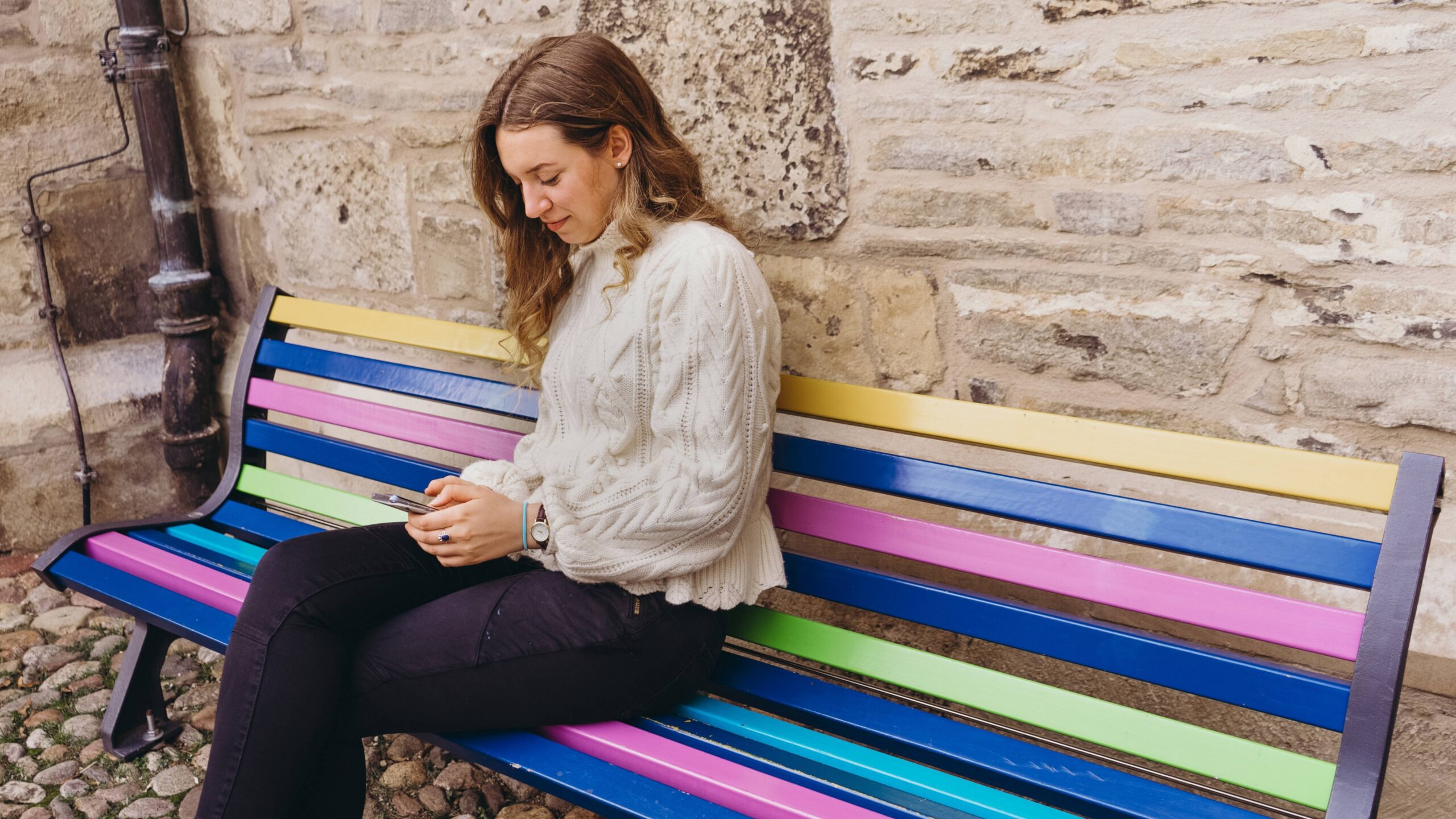 girl sitting on a bench looking at phone scaled