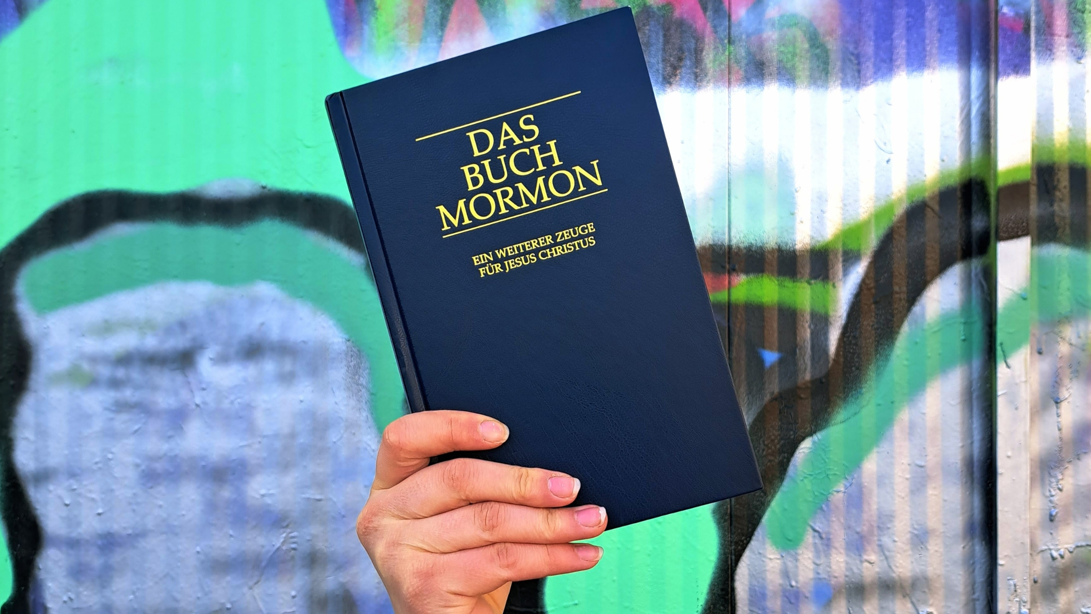 Das Buch Mormon vor einer Wand mit Graffiti